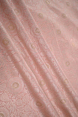 Close-up of pink fabric with intricate gold floral zari patterns