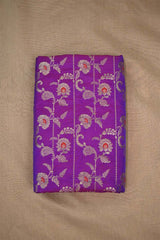 Purple Banarasi silk fabric with floral zari woven pattern and red accents on beige background