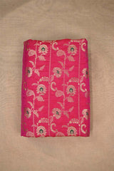 Close-up of pink Banarasi silk fabric with gold floral embroidery woven and green accents on beige background