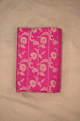 Close-up of pink Banarasi silk fabric with gold floral embroidery woven and orange accents