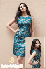 A woman wearing a blue floral Banarasi silk dress against a beige wall, with a close-up inset.