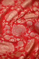 Close-up of red Banarasi silk fabric with intricate gold floral pattern