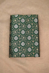 Green Banarasi silk fabric with intricate gold and silver floral pattern on beige background