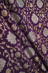 Close-up of a purple wine silk fabric with gold and silver zari woven floral pattern