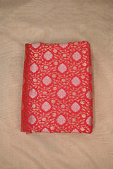 Red Banarasi silk fabric with gold and silver floral pattern on beige background