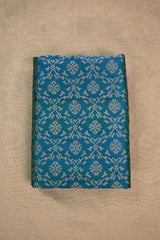 Teal Blue Banarasi Silk fabric with gold zari ikkat patterns on beige background