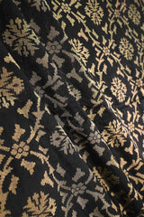 Close-up of black silk fabric with beige floral pattern woven with antique zari