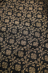 A black silk fabric with beige floral pattern woven with antique zari