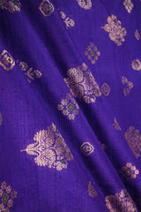 Close-up of purple blue fabric with gold and green floral patterns