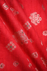 Close-up of red raw silk fabric with antique and green floral patterns
