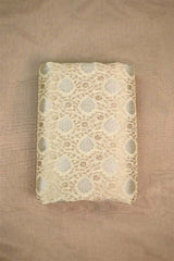 Creamish White Banarasi Silk fabric with gold and silver zari floral patterns on beige background