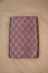 Close-up of a maroon Banarasi silk fabric with a subtle geometric pattern on beige background