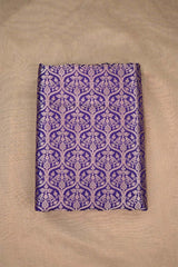Close-up of a purple Banarasi silk fabric with a subtle floral pattern on beige background