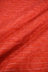 Close-up of Orange Chanderi fabric with digital floral print, fine zari vertical stripe detailing, and alternate resham woven lines