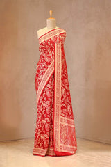 Red saree with white patterns on a mannequin against a beige background
