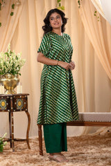 A woman in a green traditional kurti co-ord set, standing in a decorated indoor setting.