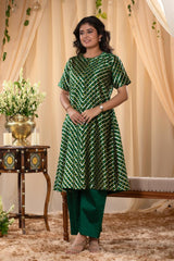 A woman in a green traditional kurti co-ord set, standing in a decorated indoor setting.