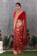 Woman wearing a red saree with gold patterns against a scenic backdrop