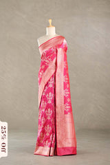 Pink Banarasi silk saree with light gold floral woven patterns draped on a mannequin against a gray background