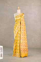 Yellow Banarasi silk saree with multicolor floral patterns draped on a mannequin against a neutral background