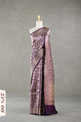 A purple Banarasi silk saree draped on a mannequin against a gray background