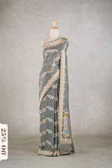 Gray saree with intricate patterns on a mannequin against a plain background