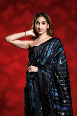 Woman wearing a black and blue party wear saree against a red background, black silk saree