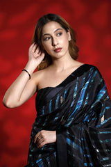 Woman wearing a black and blue party wear saree against a red background, black silk saree