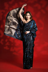 Woman wearing a black and blue party wear saree against a red background, black silk saree
