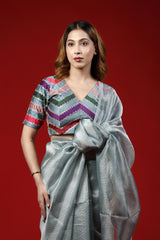 A woman wearing a colorful designer blouse with party wear saree with a red background