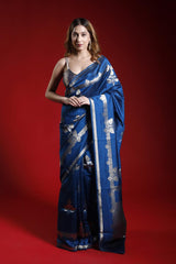 A woman wearing a blue party wear saree with silver patterns on a red background