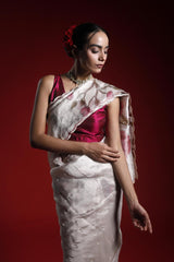 A woman wearing a party wear saree with a red and white floral pattern on a red background