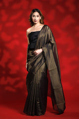 A woman wearing a black party wear saree with golden stripes against a red background