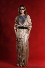 A woman wearing a golden party wear saree dress for a cocktail party looks against a red background