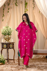 A woman in a traditional pink kaftan co-ord set, standing in a decorated indoor setting.