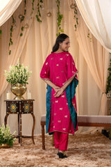 A woman in a traditional pink kaftan co-ord set, standing in a decorated indoor setting.