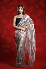 A woman wearing a light pink party wear saree with a red background