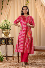 A woman in a pink traditional kurti co-ord set, standing in a decorated indoor setting.