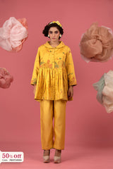 Woman wearing a yellow outfit with floral patterns against a pink background