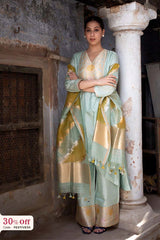 Woman in a traditional outfit standing against a stone wall with a decorative column.