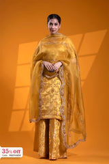 Woman wearing a yellow traditional outfit with a matching dupatta on an orange background