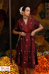 Woman in a maroon dress with white patterns standing amidst flowers, with a promotional banner in the corner.