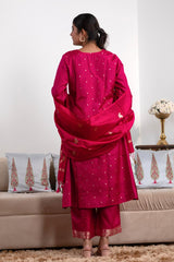 Woman in a pink traditional outfit standing in a living room.