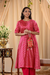 A woman in a pink traditional kurti co-ord set, standing in a decorated indoor setting.