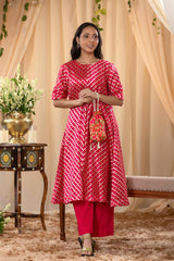 A woman in a pink traditional kurti co-ord set, standing in a decorated indoor setting.