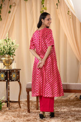 A woman in a pink traditional kurti co-ord set, standing in a decorated indoor setting.