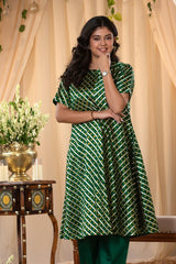 A woman in a green traditional kurti co-ord set, standing in a decorated indoor setting.