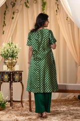 A woman in a green traditional kurti co-ord set, standing in a decorated indoor setting.