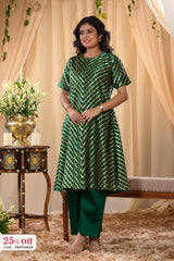Woman wearing a green and white patterned kurta with pants in a decorated indoor setting.