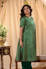 A woman in a green traditional kurti co-ord set, standing in a decorated indoor setting.